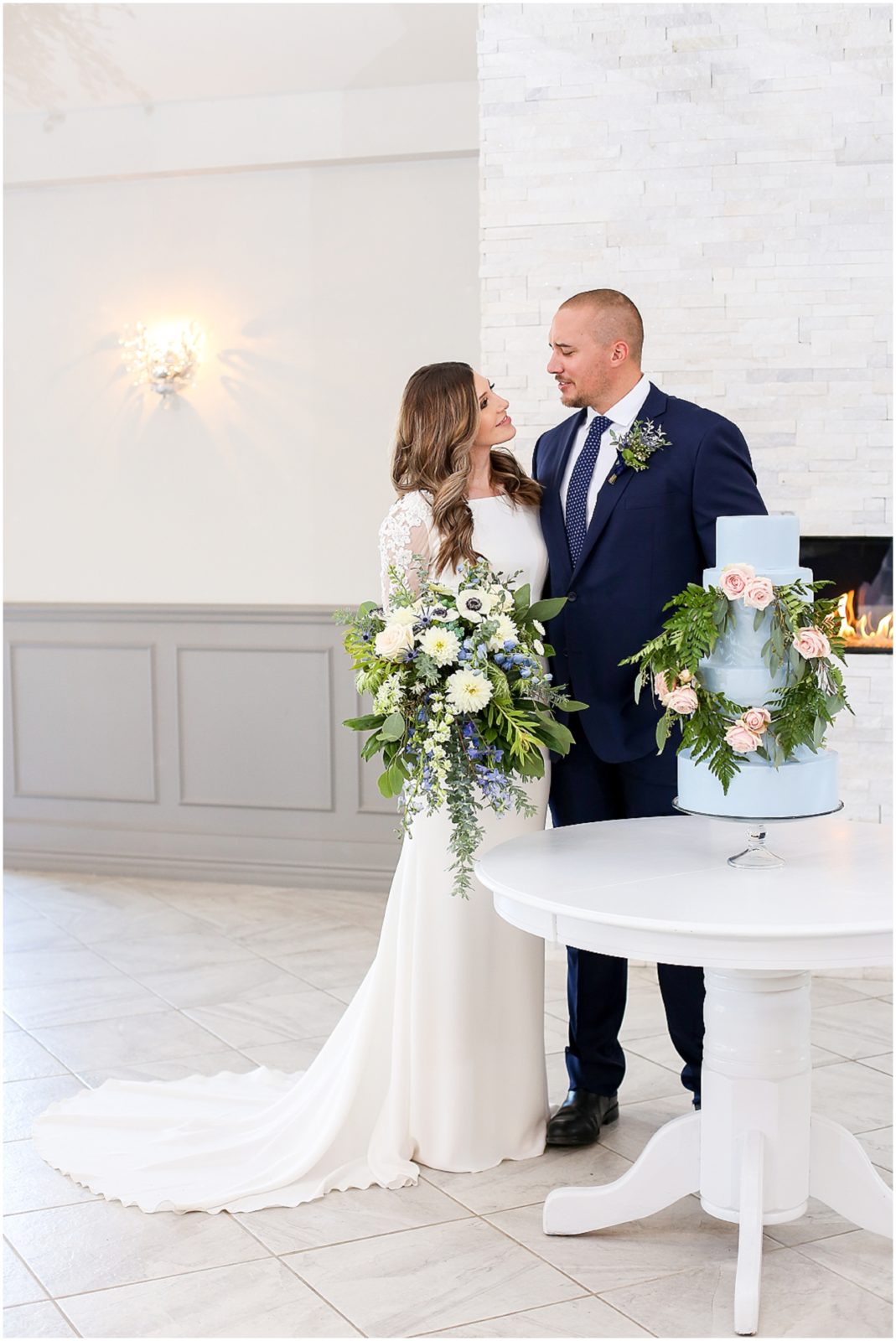 BRIDE AND GROOM LOOKING AT EACH OTHER WITH BLUE WEDDING CAKE AND BLUE WEDDING FLOWERS BY THE BEST KANSAS CITY WEDDING PLANNER