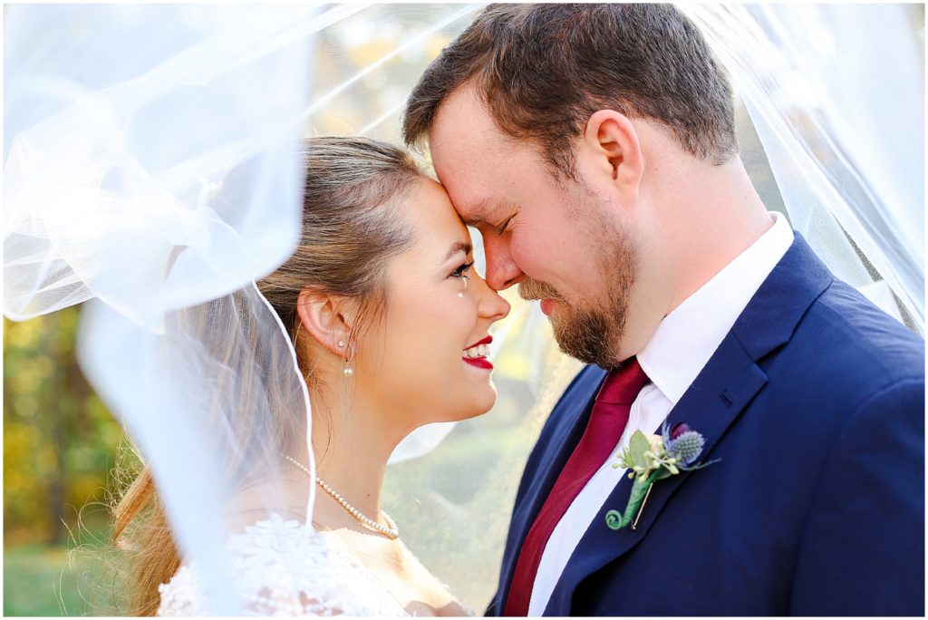 bride and groom under veil and wedding venue the Elms 