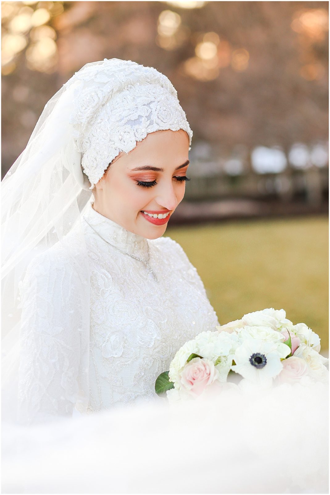 bride looking down at flowers photo with wedding veil