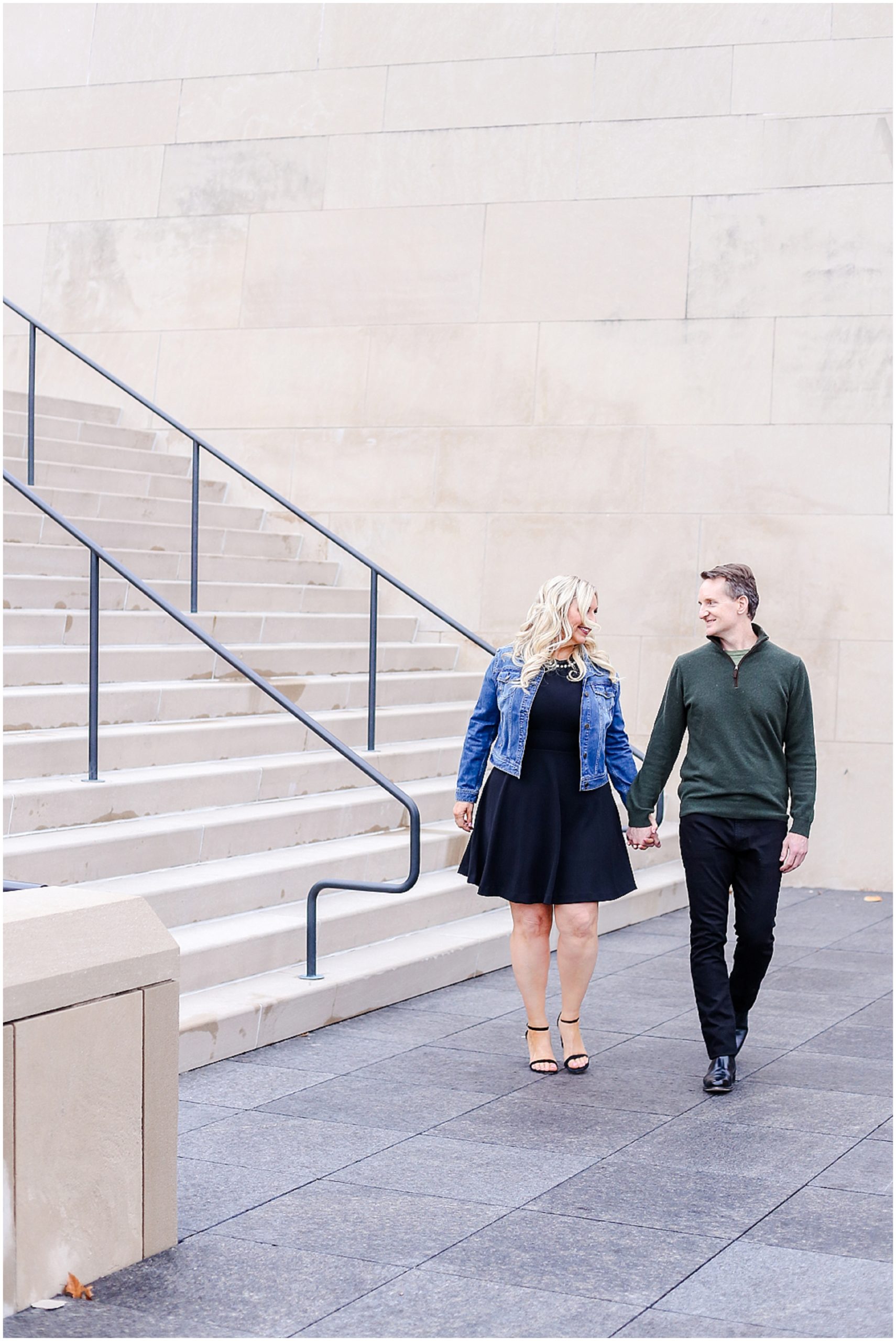 walking while holding hands for their engagement portraits kansas city