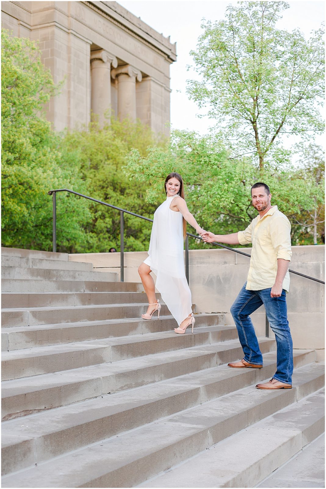 walking up the stairs for their engagement photos at kansas city nelson atkins museum