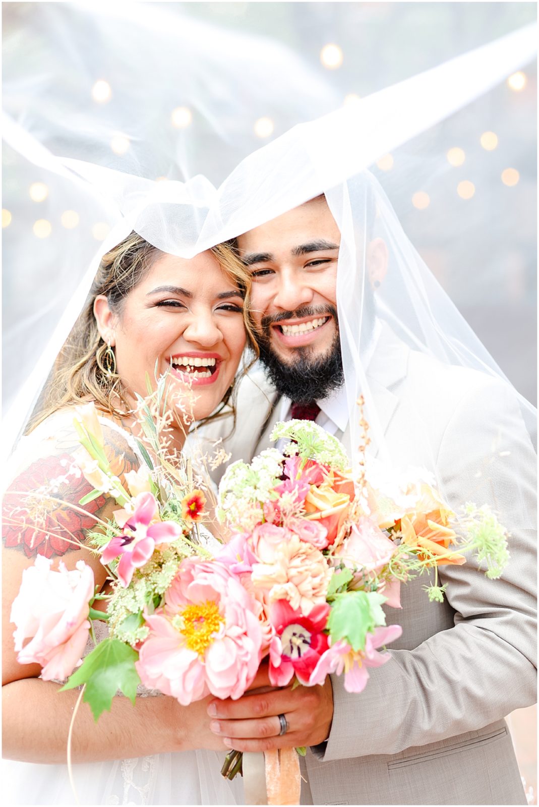 bride and groom under wedding veil laughing photo