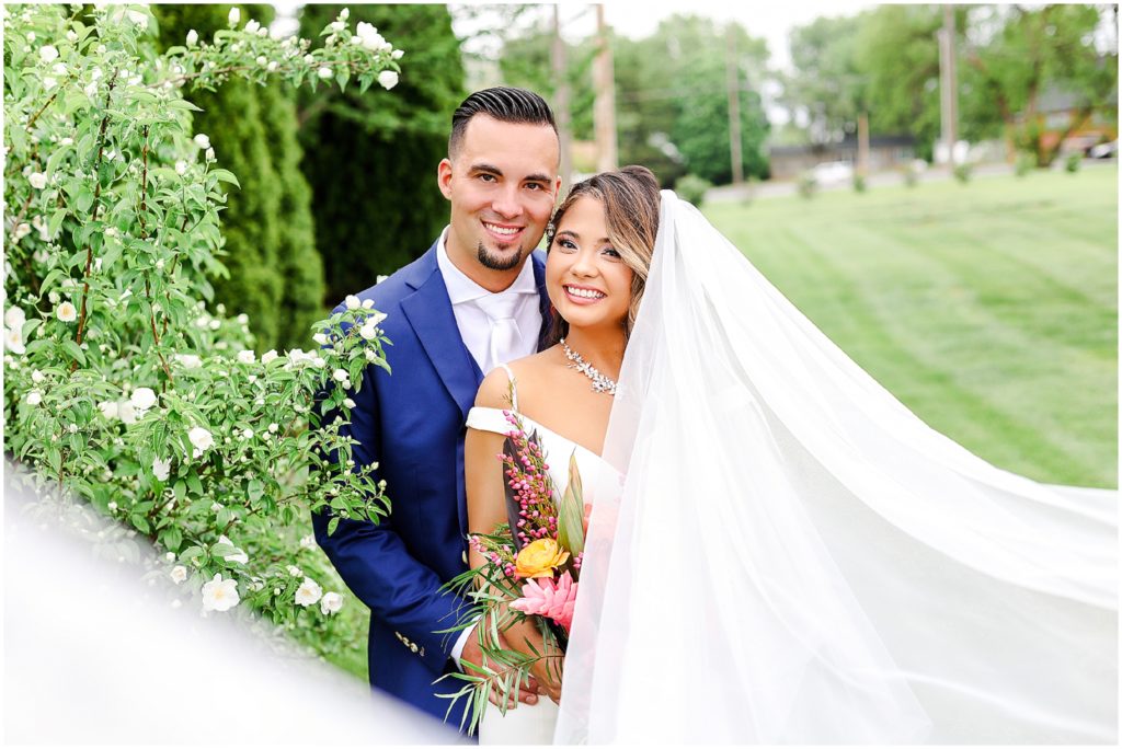 Gorgeous Bride & Groom Wedding Photos taken at the Kansas City Wedding Venue - Rhapsody - by Mariam Saifan Photography - Long Wedding Veil - Lace Wedding Dress - Tropical Wedding Theme