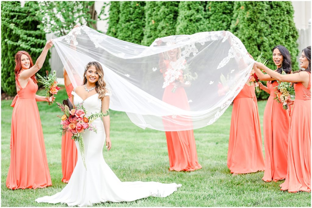 bridal party having so much fun - throwing long wedding veil in the air 