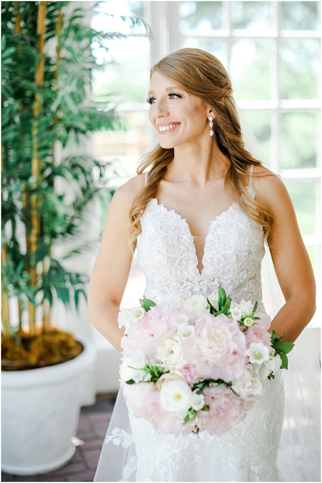 beautiful bride looking out the window wearing lace wedding dress