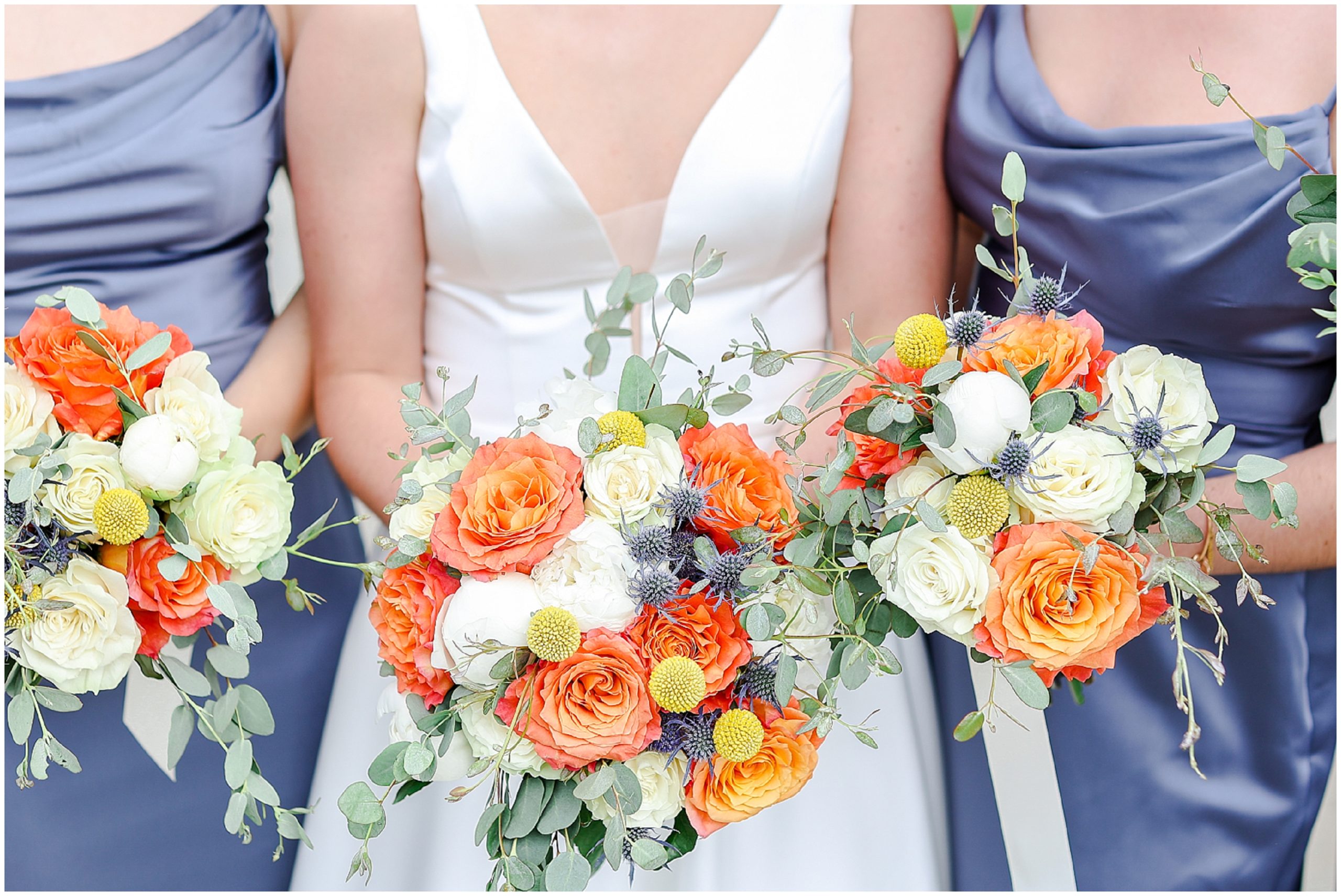 blue bridal party with orange flowers 